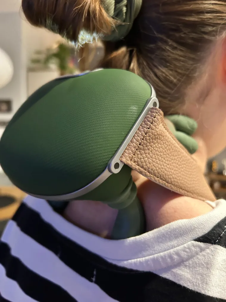 Het massageapparaat om de nek en schouders gedragen, van achteren gezien, verstelbare band op zijn plek